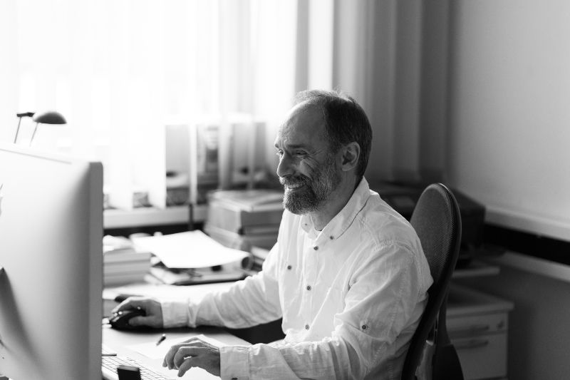 Portrait Cyrus Tahbasian am Schreibtisch und Computer – Foto by Michael Kestin